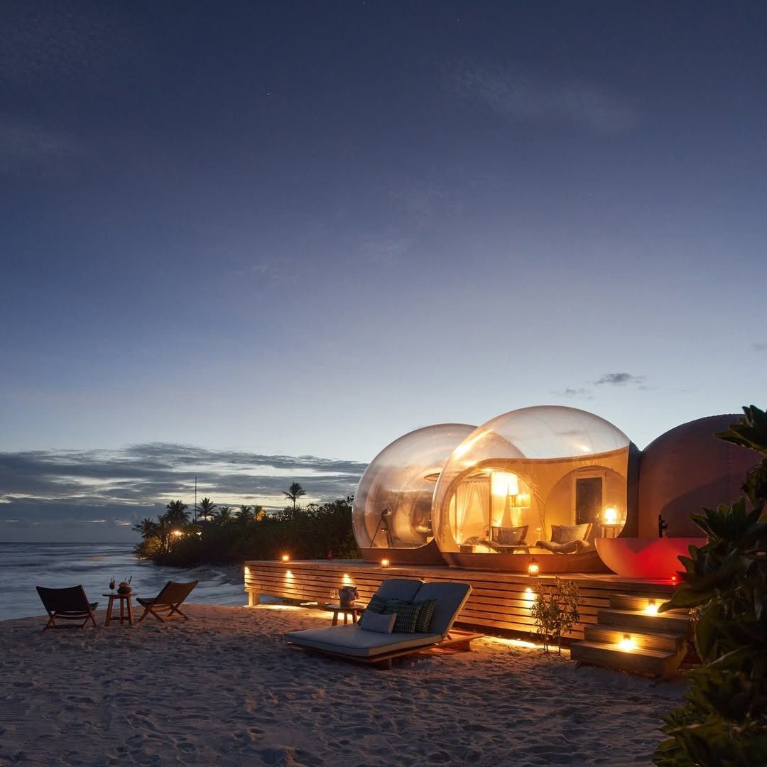 Lit bubble suite on a quiet beach at dusk