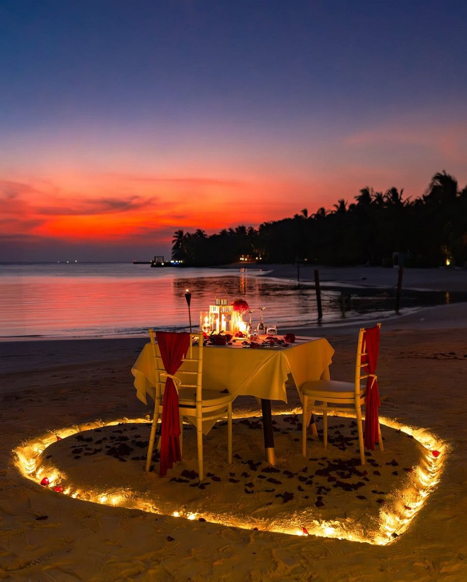 Candlelit dinner set on the sand at sunset