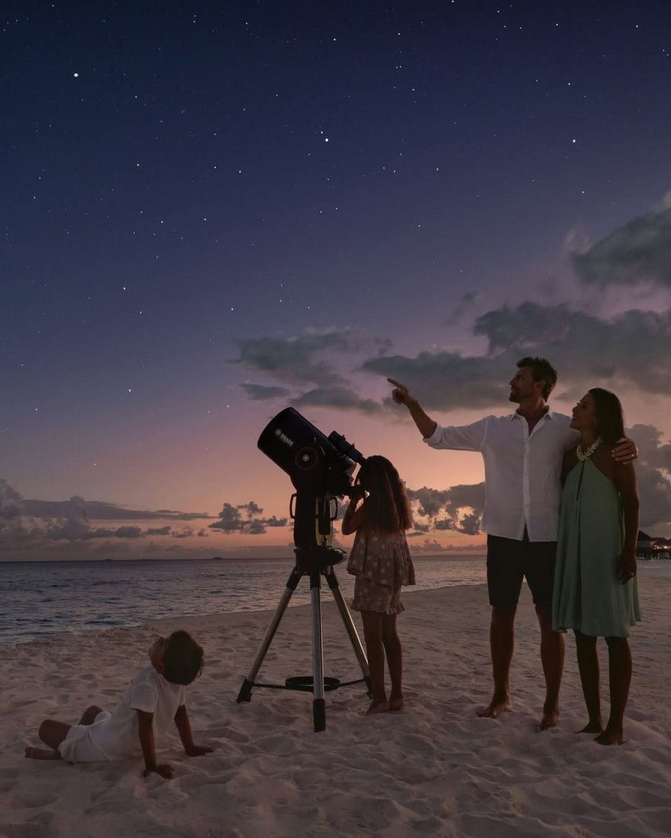 Family stargazing through a telescope on the beach